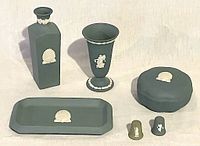 All six items arranged: rectangular tray, two vases of different heights, lidded dish, and two thimbles. Matte-soft green jasperware with cream classical motifs clearly visible.