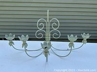 Side view showing five extended arms with lotus flower candle holders and scroll wall mount detail, painted matte gray-green.
