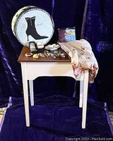 Whole lot arranged on and around a small wooden side table with a lace-trimmed hatbox in background and various jewelry and wristwatches on the table.