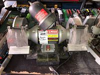 Front view of Craftsman bench grinder showing dual grinding wheels with metal guards and lamp on top.