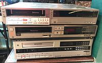 Three stacked video cassette recorders: Sony Betamax SL-2300, Sony Betamax SL-2500, and Sanyo Betacord VCR 4660. Visible buttons, displays, and labels.