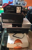 Stacked view showing boxed Realistic Nova Pro and Sansui headphones on top of Sanyo VCR and Agfa Snapscan scanner.