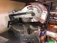 Side view of Craftsman miter saw showing blade, handle, and adjustment knob on a shelf.