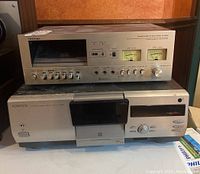 Stacked Toshiba stereo cassette deck on top of Kenwood multiple CD player showing front panels and controls.