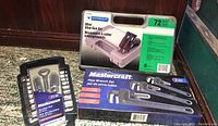 Mastercraft pipe wrench set box, mini glue gun kit box, and socket set case on floor