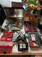 Overview of all tools on table including clamps, drill bit sets, vice grips, tool belts.
