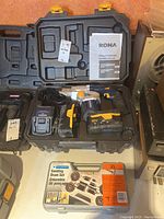 Rona 18V cordless nailer with battery, charger, and manual inside a black plastic carrying case beside a Mastercraft sanding drum set in a plastic case.