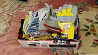 Box of assorted new work gloves in various materials and colors.