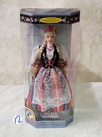 Front view of the Barbie doll in original packaging showing the doll dressed in Polish traditional costume with floral crown and lace apron.