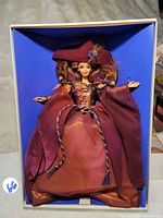 Full view of Autumn Glory Barbie doll dressed in a burgundy and orange autumn-themed dress with a matching hat inside the original box.