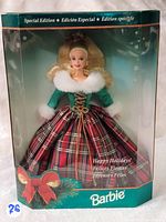 Front view of the Barbie doll in original box showing the red and green plaid dress with fur trim and holiday packaging graphics.
