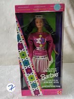Front view of boxed Native American Barbie doll showing doll in traditional pink attire and part of the packaging design.