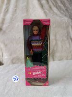 Front view of the boxed 1994 Tree Trimming Barbie doll showing the doll wearing a colorful knit sweater and accessories, inside original packaging.