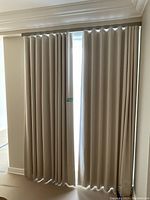 Two full-length beige drapery panels hung on matching track in doorway opening