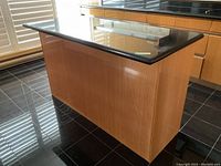 View of side panel of kitchen island with bamboo wood base and polished black granite countertop.