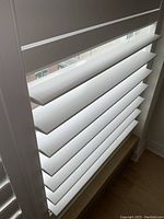Close-up showing the horizontal slats and frame of a white California shutter with natural light filtering through.