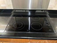 Top-down view of cooktop installed in black countertop showing four radiant elements and right-side controls.
