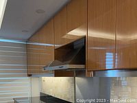 Range hood installed under wooden cabinetry above stove with a stainless steel finish.