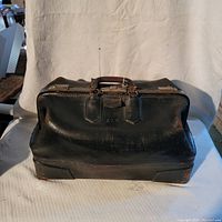 Front view of the black antique leather doctor's bag showing the overall shape and brass closures.
