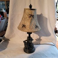 Front view of the full 21 inch tall antique ebony carved elephant lamp with palm tree patterned lampshade