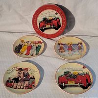 Front view of all four decorative canape plates showing vintage style illustrations and the red circular box lid with branding.