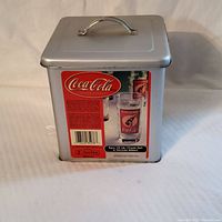 Metal tin case for the Coca Cola glass set, showing product label and branding.