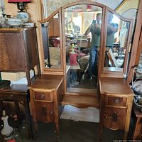 Front view of antique vanity dresser with central mirror and two folding side mirrors, showing overall design and wood finish.