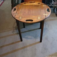 Butler tray table with sides flat showing wood surface and handles.