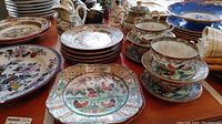Overview of the rooster themed china collection showing various plates, teacups, creamer, and sugar bowl with colorful rooster and floral decorations.