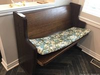 Full view of the wooden church pew with floral cushion placed on seat showing overall condition and wear.