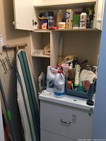 Photo of cabinet with cleaning supplies including sprays, bleach, boxed soap, and cleaning cloths