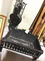 Heavy-duty cast iron fireplace grate with a grid design for supporting firewood inside a fireplace.