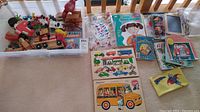 Full display of vintage children's toys, puzzles, books, stickers, and coloring supplies arranged on beige carpet