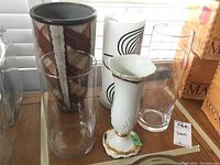 Group photo showing all five vases including three tall glass, the pottery vase with brown/gray pattern, and the white porcelain vase with gold trim.
