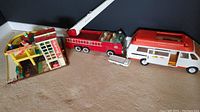 Three vintage toys displayed on floor: Little People garage, Tonka fire truck, and Tonka ambulance.