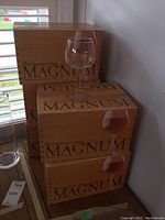 Stack of five original cardboard boxes labeled 'MAGNUM' by Royal Leerdam Holland with one clear balloon wine glass placed on top.