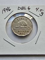Close-up photo of 1946 Canadian 5 cents coin showing double 6 error on date in clear focus, coin held in cardboard protective holder, showing octagonal shape and beaver design.
