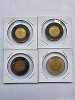 Four circulated Canadian toonies in cardboard coin holders: two 2022 Queen's dark toonies, one 2017 Vimy Ridge, and one 1999 Nunavut.