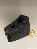 Black plastic car ramp featuring textured top and yellow rope, against white background.