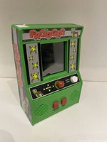 Front angle of the green Frogger Mini Arcade Game, showing the screen, joystick, buttons, and Frogger branding.