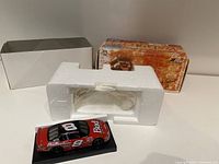 Miniature NASCAR diecast car on black base with white styrofoam insert and original box