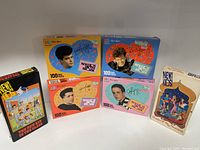 Photo showing five boxes of New Kids on the Block 100 piece puzzles featuring individual portraits and autograph prints of band members in bright colored background packaging.
