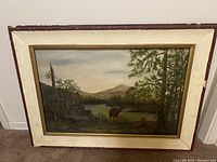 Full front view of framed oil painting showing entire landscape scene with moose by lake