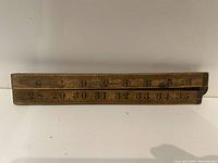 Photo of one side of the wooden meter stick with large numbers 1 to 35 visible and groove along the edge