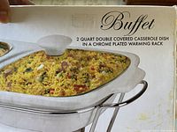Close-up image showing the dish filled with food and the label saying 'Buffet 2 quart double covered casserole dish in a chrome plated warming rack'.