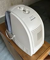 Front and side view of the Honeywell Quietcare humidifier showing control knobs, Honeywell logo, and vent openings.