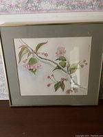 Front view of framed watercolour artwork showing Japanese cherry blossom branch with pink flowers and green foliage.