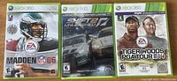 Front covers of three Xbox 360 game cases: Madden NFL 2006, Shift 2 Unleashed, Tiger Woods PGA Tour 14