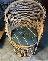 Front view of rattan chair with cushion, showing woven lattice and round cushion with plaid pattern.