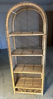 Front view of rattan shelf with four tiers and arched top.